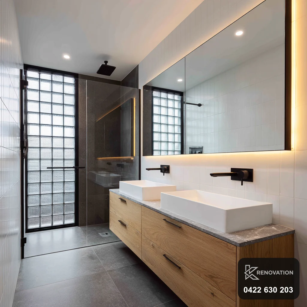 Twin-basin bathroom with dark-tiled shower in a Spotswood renovation by KRenovation