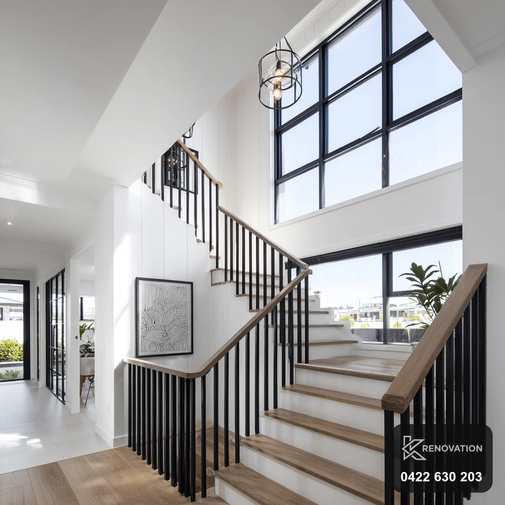 Double-height living void with black-framed windows and staircase by KRenovation