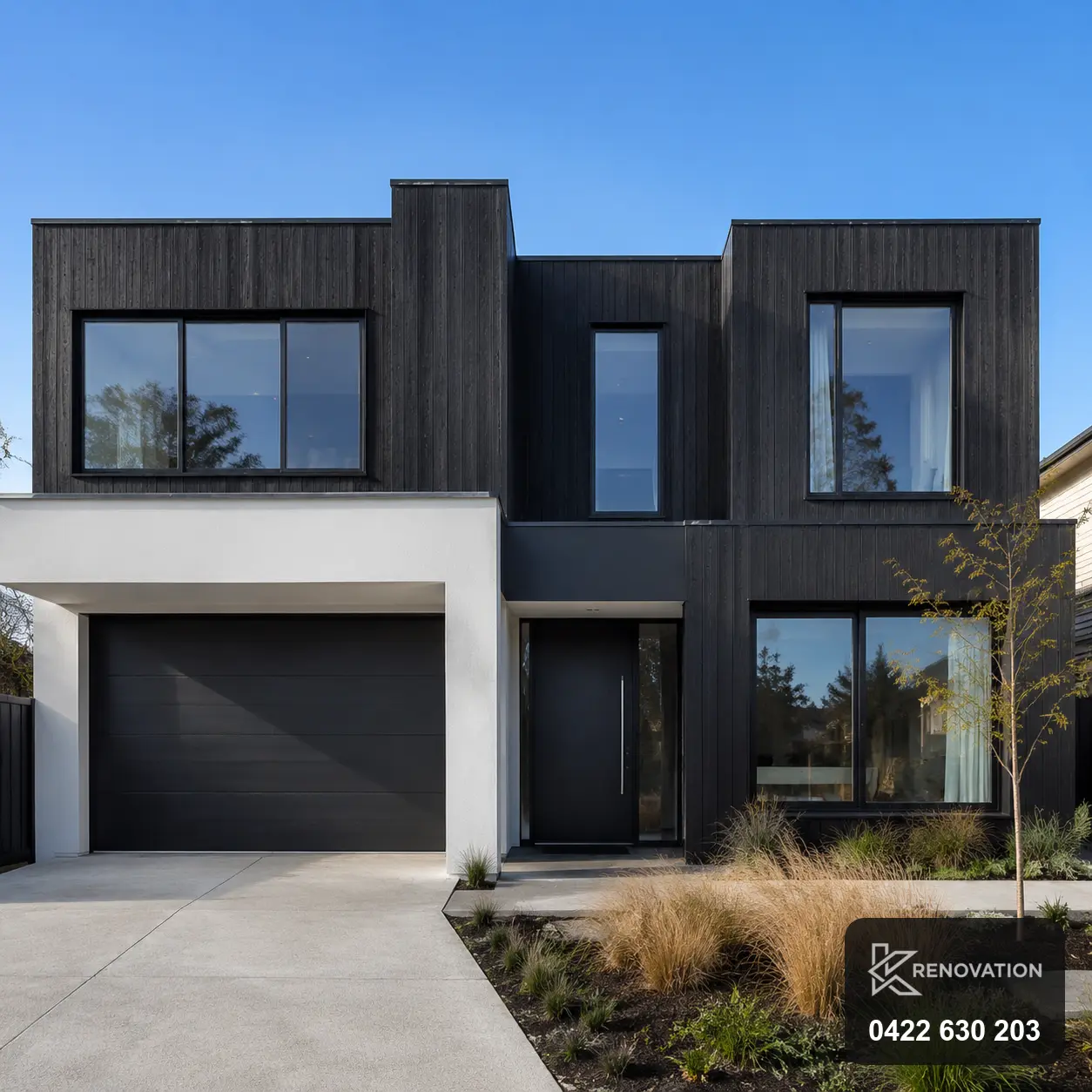 Renovated two-storey home facade with dark cladding and garage at dusk by KRenovation