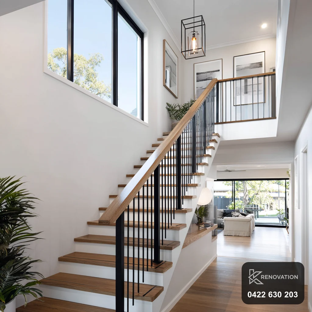 New timber staircase with black balustrade and double-height windows in a home extension by KRenovation