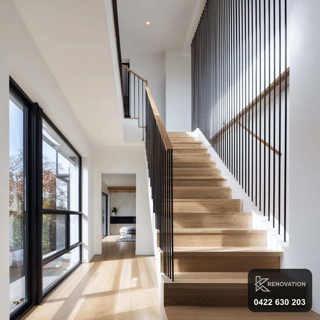 Double-height void with black-framed glazing and timber staircase in an extension by KRenovation